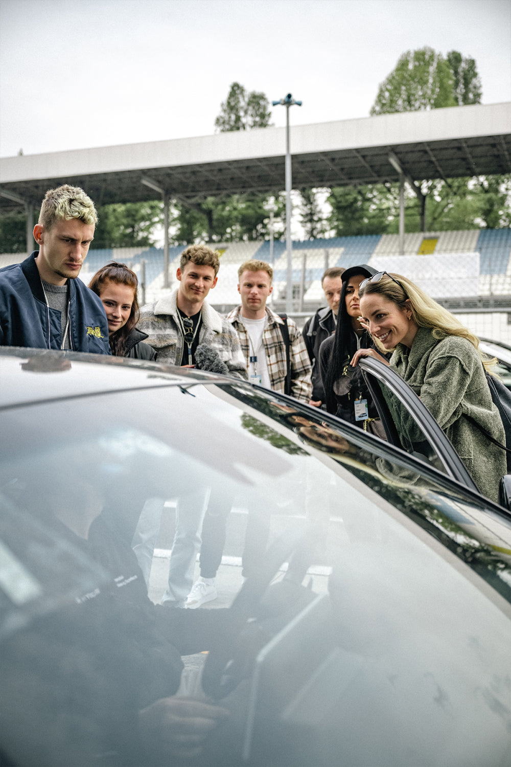 Group of seven people gathering around a Hyundai car at a racetrack in Monza.
